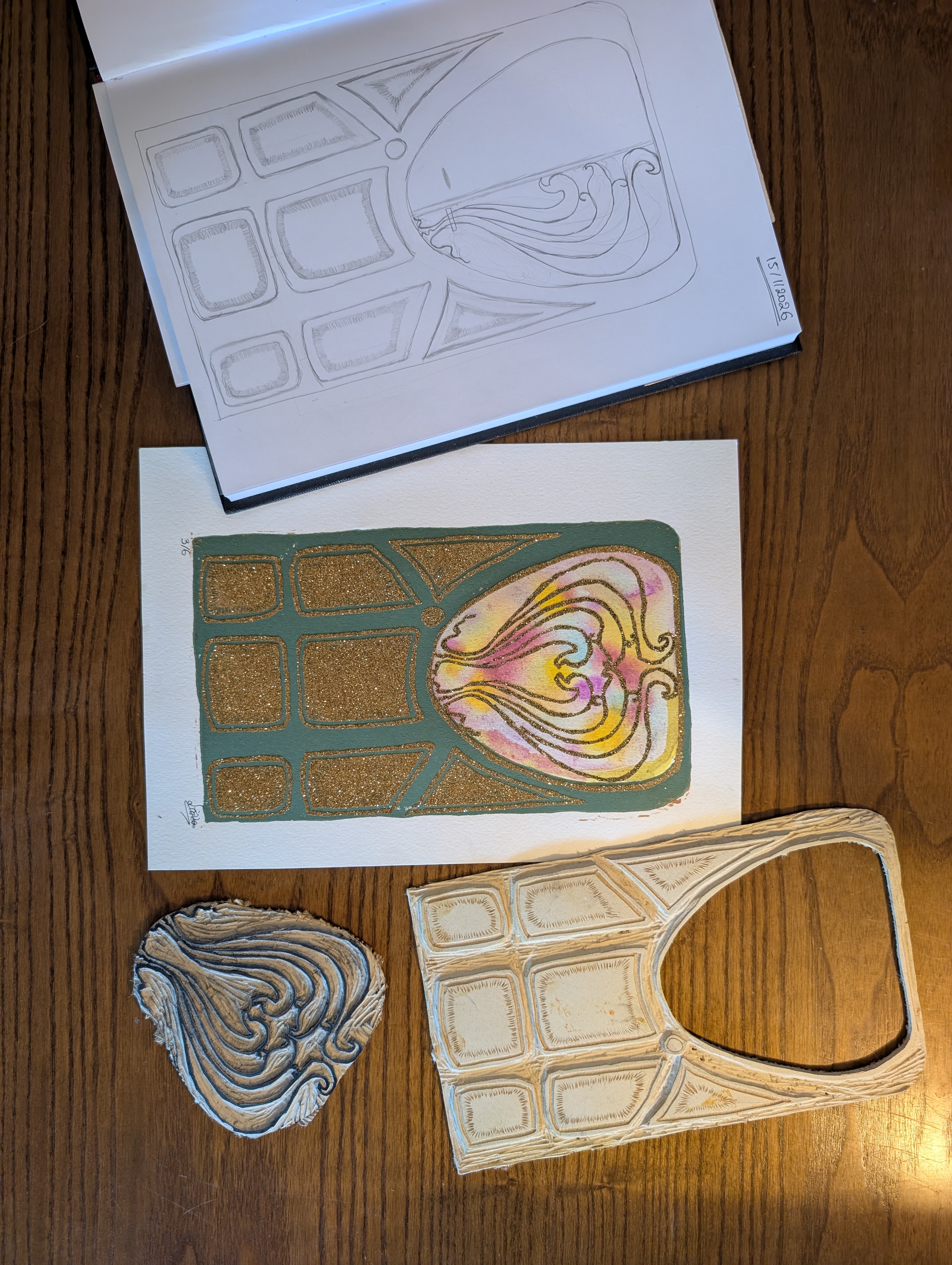 A process photo documenting the creation of an Art Nouveau-inspired reduction linocut print. On the left is a pencil sketch of a stylized door design, in the center is the completed print with a muted green frame, metallic gold accents, and a pastel stained-glass window motif and on the right are the carved linoleum blocks used to print the different layers. Together they illustrate the progression from initial drawing to carving and the final handmade print.